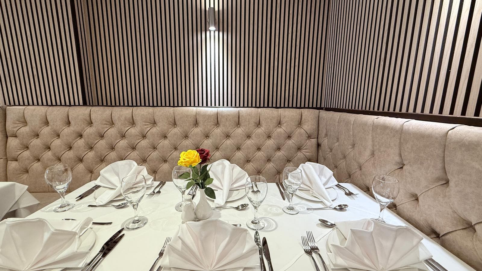 Tufted cream banquette seating with tables set for dinner