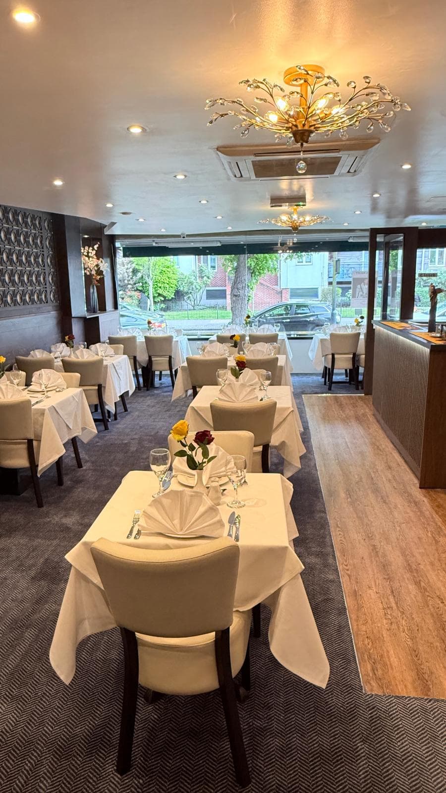 Tufted cream banquette seating with tables set for dinner at Maidenhead Spice