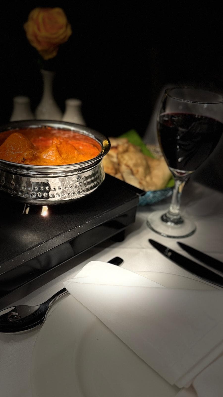 Curry in a balti dish served with bread and red wine